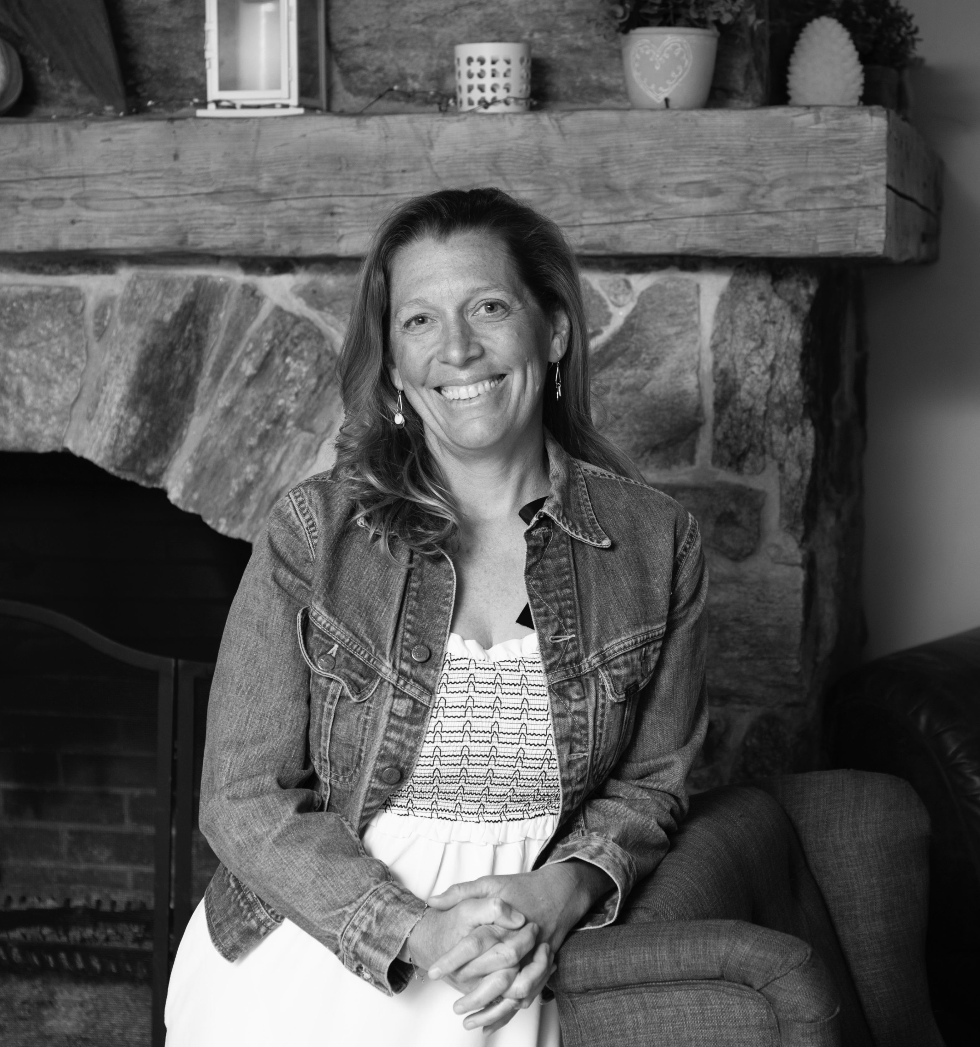 black and white of a lady in front of a fireplace